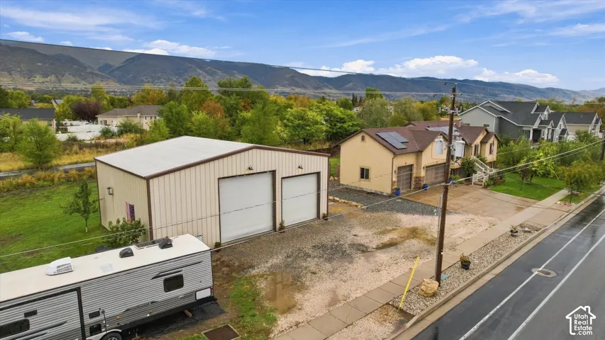 Detached two-car metal workshop, multi-level residential structure with solar panels, and mountain backdrop