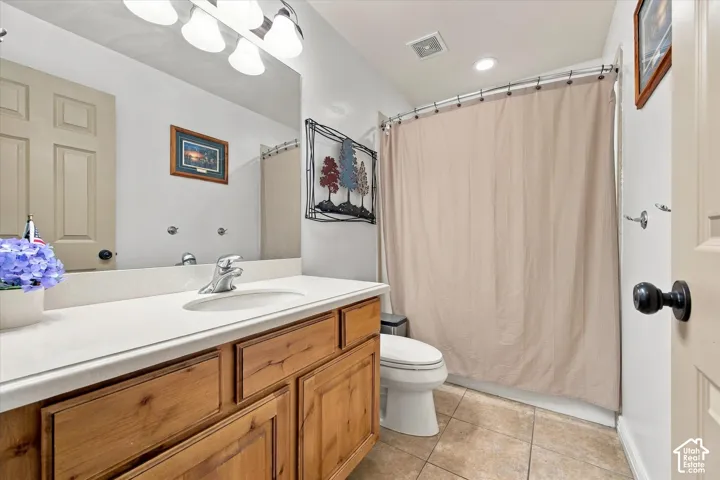 Bathroom featuring a vanity with a light-tone countertop, an undermount sink, a large wall-mounted mirror, and tile flooring