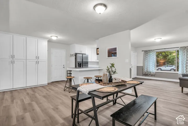 Kitchen area featuring floor-to-ceiling white cabinetry, wood-finish flooring, a white-topped kitchen island, recessed ceiling lighting, and a large window with exterior exposure