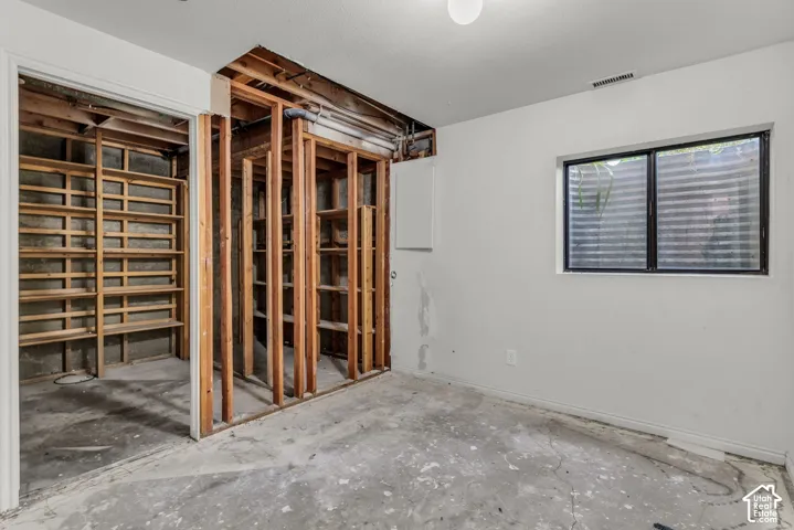 Room featuring exposed wood framing, built-in wooden shelving, and a rectangular window