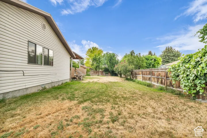 Exterior side yard featuring horizontal vinyl siding, multi-pane windows, and a wood privacy fence