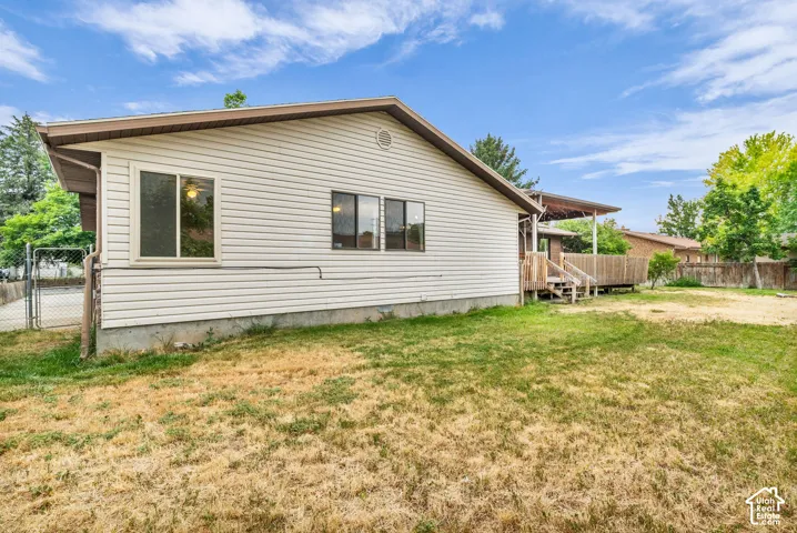 Light-colored vinyl siding exterior, rear wooden deck, and chain-link fencing