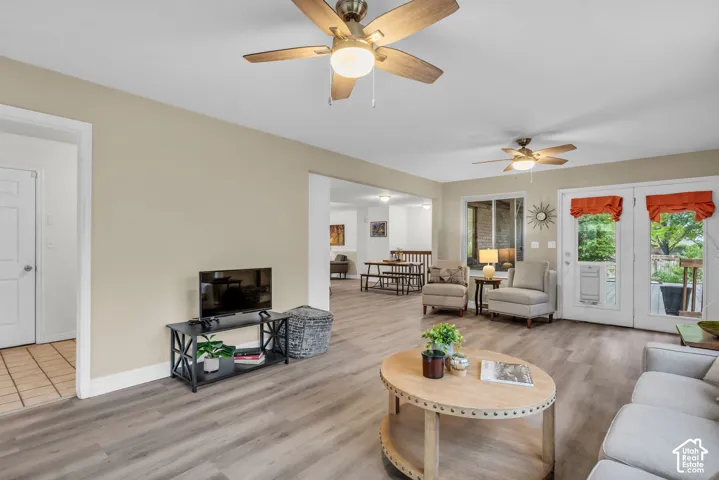 Wood-finish flooring, dual ceiling fans with integrated lighting, and double glass-paned doors with exterior access