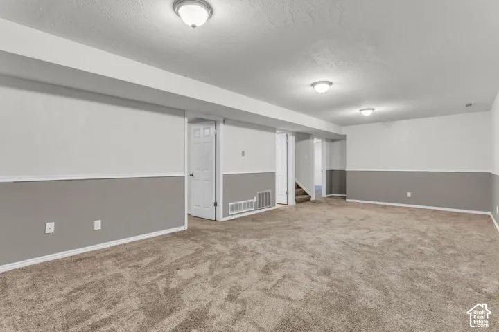 Neutral-toned interior space featuring carpeting, two-toned wall paint with chair rail molding, and three flush-mount ceiling light fixtures