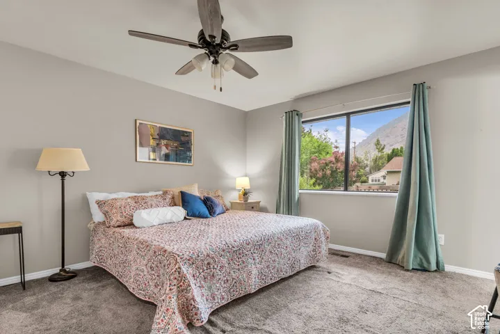 Neutral wall tones, carpeted flooring, large picture window with mountain backdrop, and ceiling fan with integrated lighting