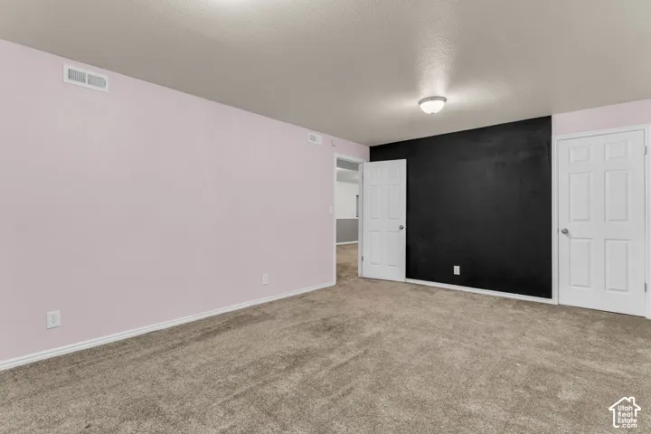 Interior room featuring neutral wall-to-wall carpeting, a contrasting black accent wall, and six-panel interior doors