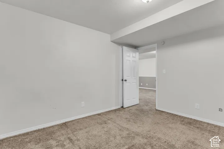 Interior room featuring neutral-toned carpeting, white walls, and a six-panel door