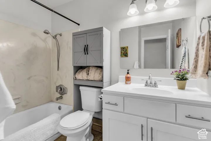 Bathroom featuring a white vanity with an integrated basin, polished chrome faucet, large wall-mounted mirror, three-light fixture, and a tub-shower combination with a surround