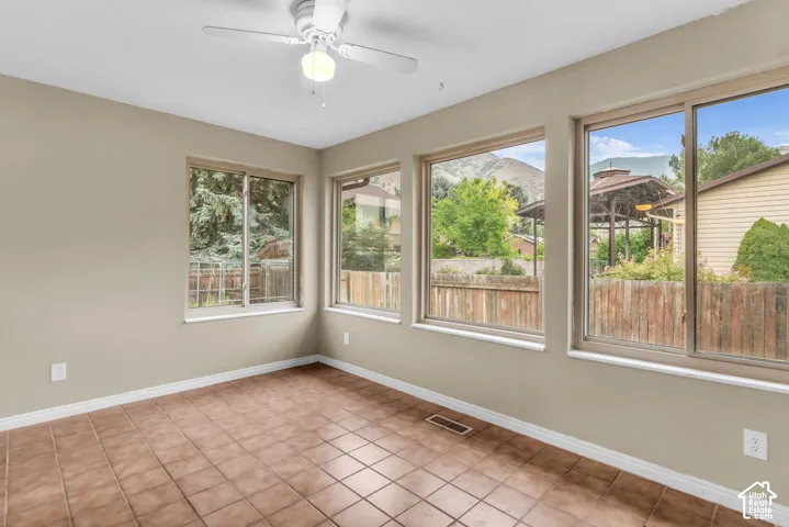 Sunroom featuring tile flooring, a ceiling fan, and large windows with mountain scenery