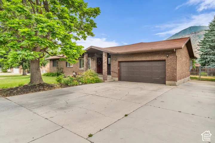 Single-story brick exterior featuring a multi-car garage, covered entryway, and mountain backdrop