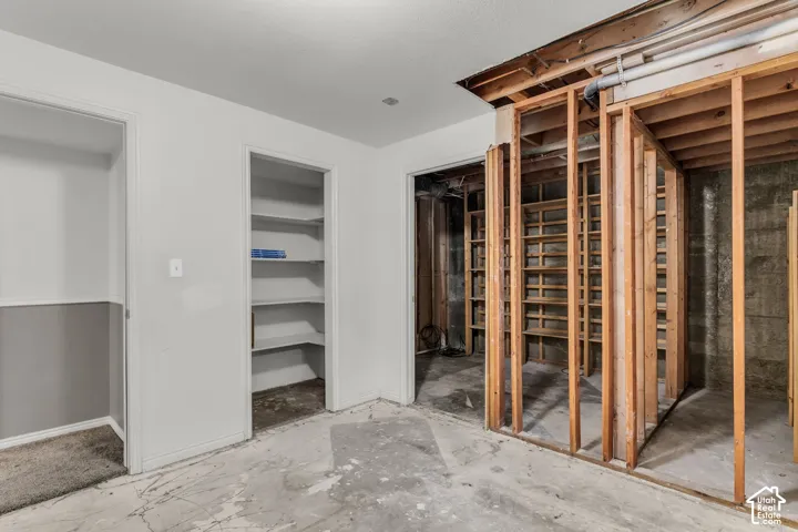 Interior space featuring exposed wood wall framing, built-in recessed shelving, concrete flooring, and finished drywall surfaces