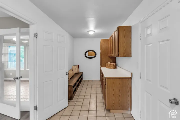 Utility area featuring tile flooring, built-in wooden cabinetry with solid-surface countertops, and a recessed ceiling light fixture