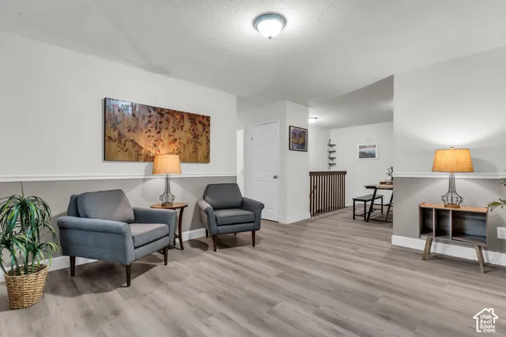 Interior space featuring wood-finish flooring, two-tone wall paint with chair rail molding, a neutral color palette, and a wooden banister with vertical spindles