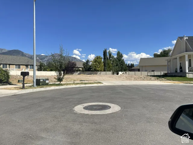 Vacant residential lot situated on a cul-de-sac, featuring mountain scenery and perimeter fencing