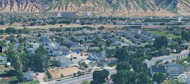 Aerial perspective featuring a residential lot situated within a developed neighborhood, highlighted by prominent mountain range topography