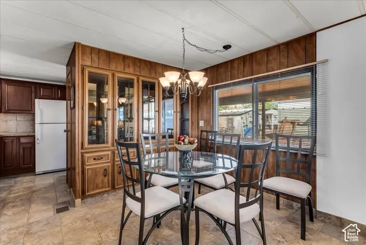 Built-in wood-finish cabinetry, tile flooring, multi-light hanging chandelier, and horizontal window blinds