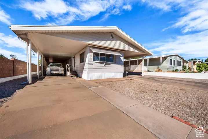 Exterior siding, metal roof, attached carport, and low-maintenance gravel landscaping