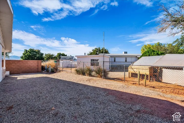 Expansive gravel backyard featuring a perimeter masonry wall, chain-link fencing, and a detached exterior structure