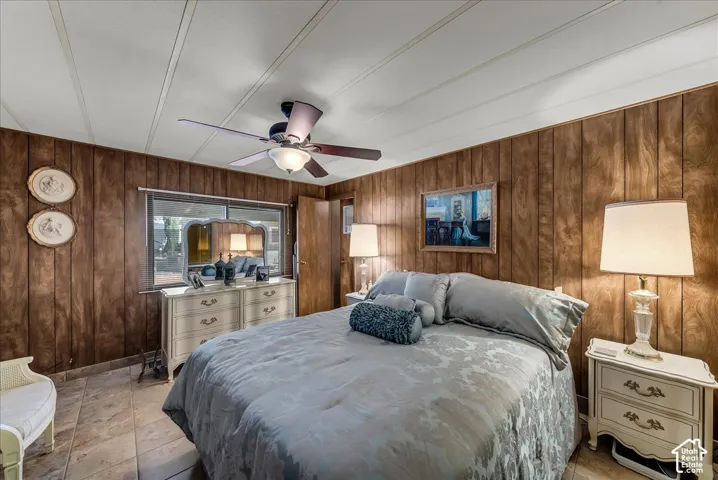 Room featuring wood-paneled walls, tile flooring, and a ceiling fan with integrated lighting