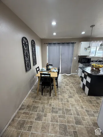 Kitchen area featuring recessed ceiling lighting, multi-tonal tile flooring, and a stone-topped island with a decorative checkered base