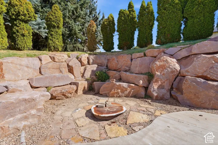 Terraced stone retaining wall with integrated plantings, flagstone patio, and a stone-edged fire pit