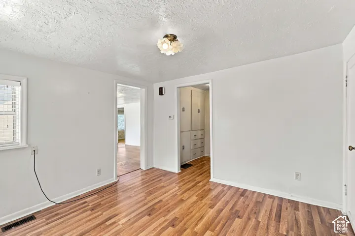 Wood-finish flooring throughout, white painted walls, and a ceiling-mounted light fixture