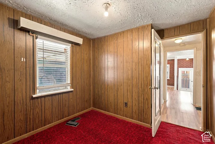 Wood-finish wall paneling, red carpeting, window with horizontal blinds, and a built-in overhead light fixture