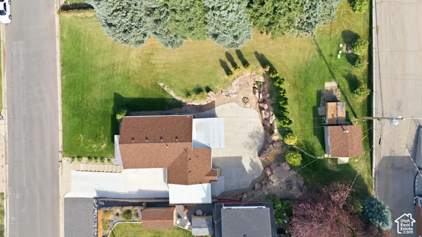 Spacious property featuring a large lawn, extensive concrete paving, a multi-level rock garden, and mature trees