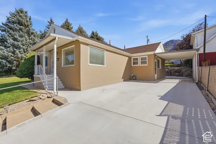 Stucco exterior with a covered front porch, white railings, and a concrete driveway