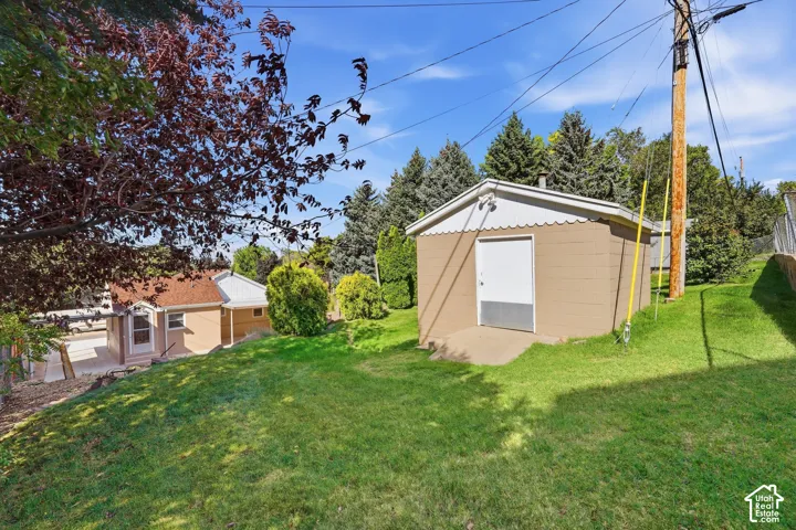 Expansive sloped lawn with mature trees and a detached structure