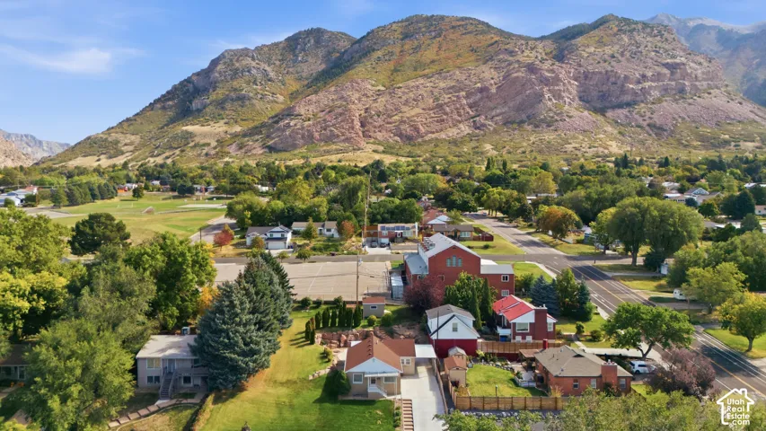 Expansive mountain backdrop with a residential neighborhood featuring established trees, paved streets, and a large open green space