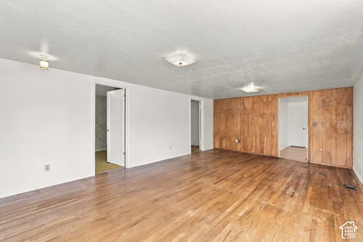 Wood-finish flooring, white walls, wood paneling, multiple doorways, and ceiling-mounted light fixtures