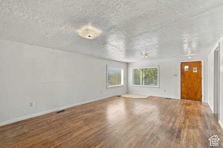 Wood-finish flooring throughout, white walls, and multiple windows with blinds