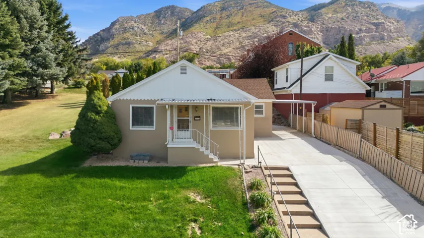Single-story residence with a covered front porch and a long concrete driveway, featuring an attached carport