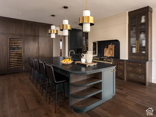 Spacious kitchen featuring an expansive island with a dark countertop, integrated wine refrigerator, ample built-in cabinetry, and hardwood flooring