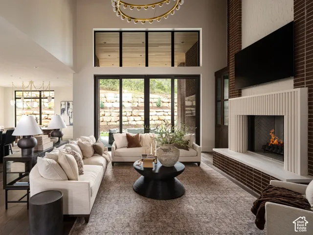Two-story living area featuring a prominent brick fireplace with a light-toned mantel, large sliding glass doors, and a high ceiling