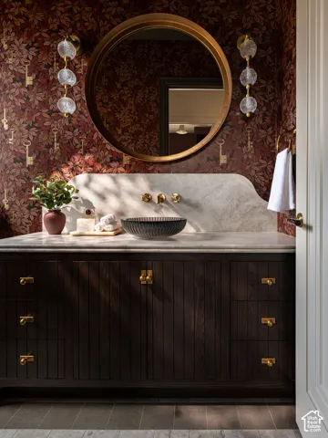 Dark wood-finish vanity with brass hardware, a light-toned countertop, and an undermount basin