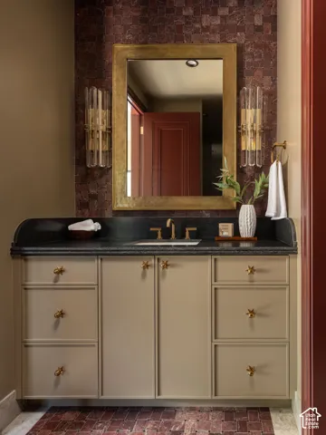 Custom vanity with gold-tone hardware, dark countertop, and integrated sink