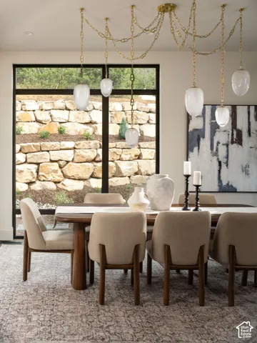 Dining area featuring a wood-finish table, upholstered chairs, and a multi-pendant brass light fixture