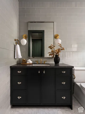 Black vanity with integrated sink, gold-tone fixtures, wall-mounted sconces, and rectangular mirror