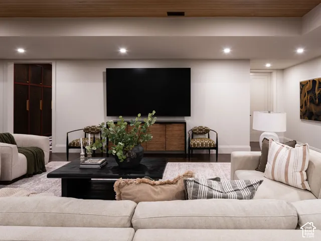 Recessed lighting, wood-finish ceiling paneling, built-in media console, dark wood-finish flooring, and a built-in storage unit