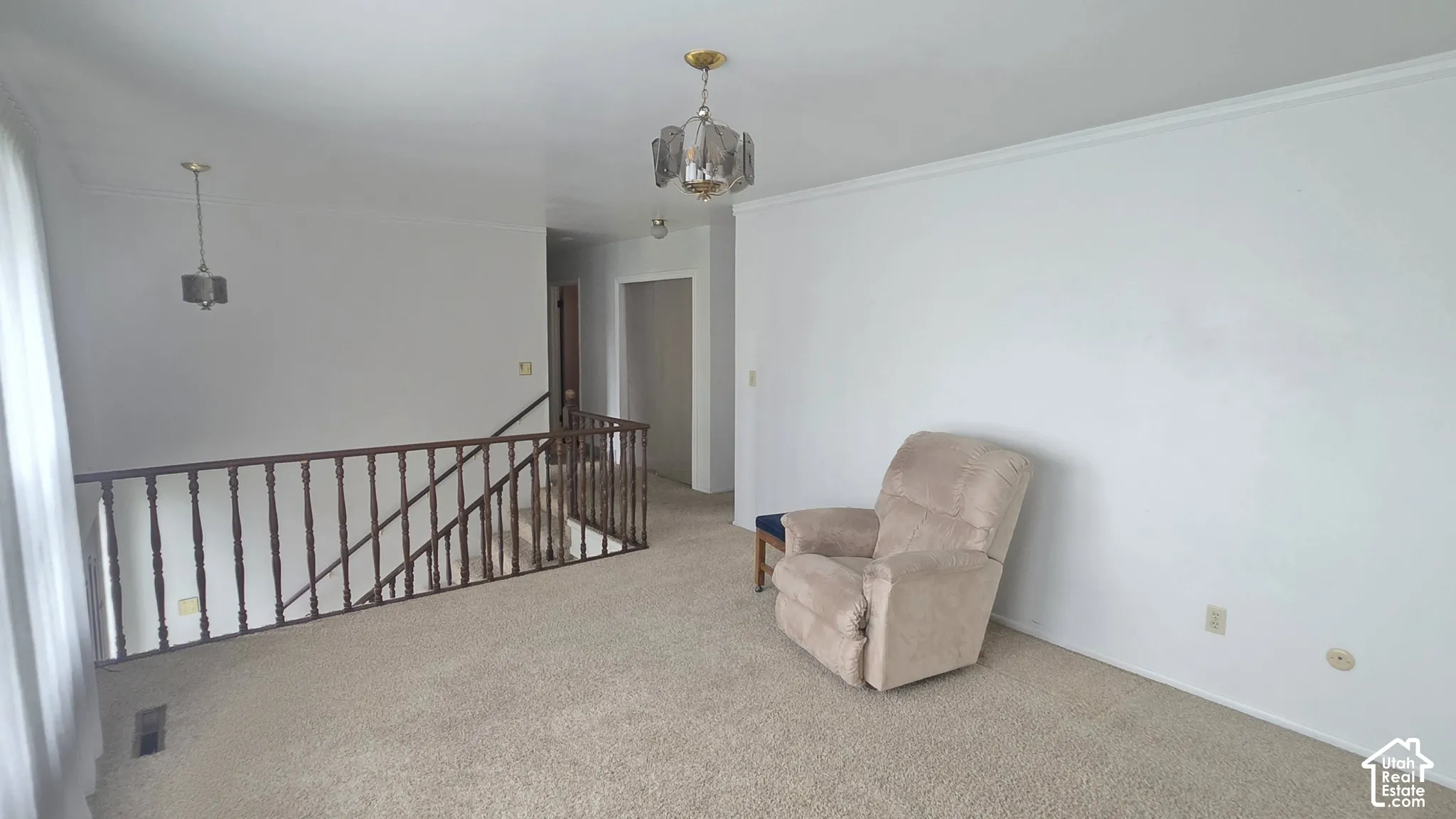 Neutral-toned carpeting, wood-finish balustrade, and two multi-light pendant fixtures