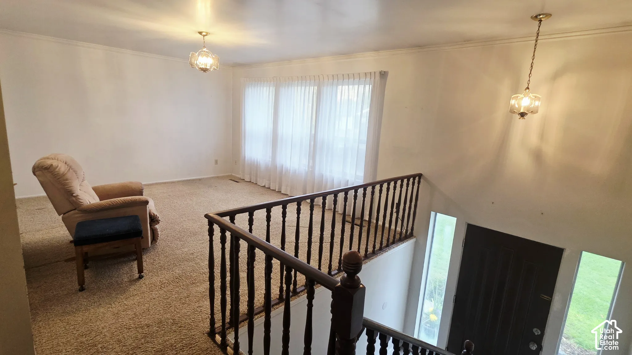 Large room featuring wall-to-wall carpeting, wood-spindle railings, two glass globe pendant lights, and a floor-to-ceiling multi-panel window configuration