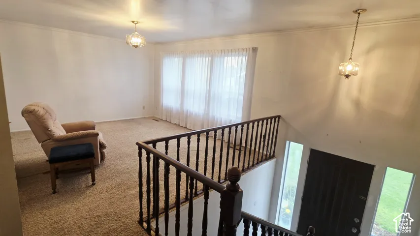 Large room featuring wall-to-wall carpeting, wood-spindle railings, two glass globe pendant lights, and a floor-to-ceiling multi-panel window configuration
