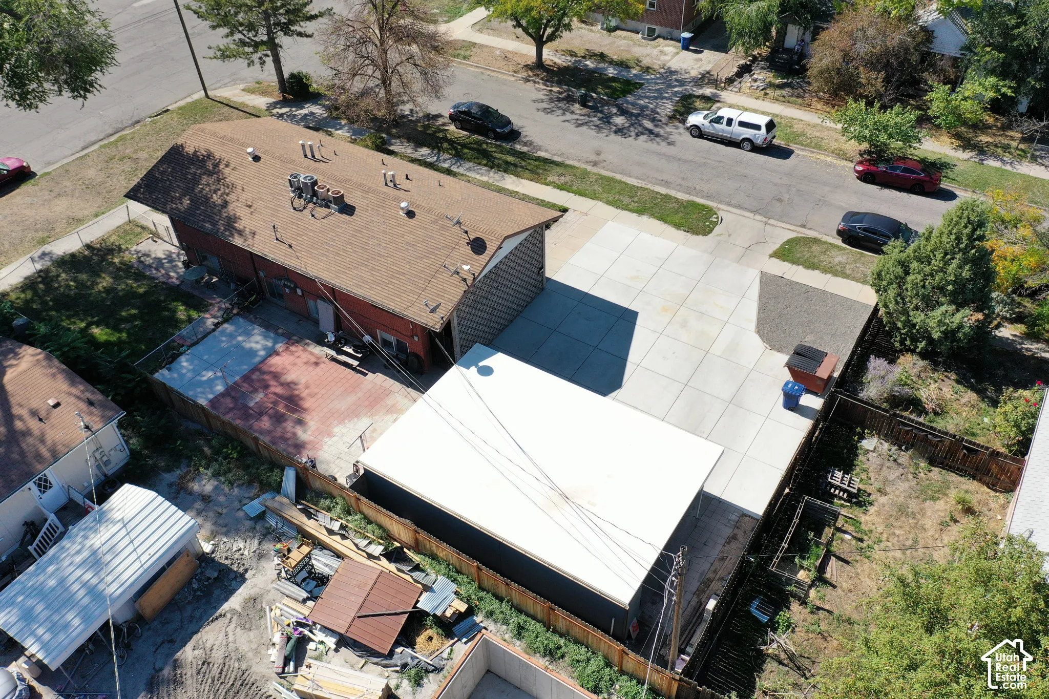 Expansive concrete driveway, fenced property, and detached outbuilding with a flat roof