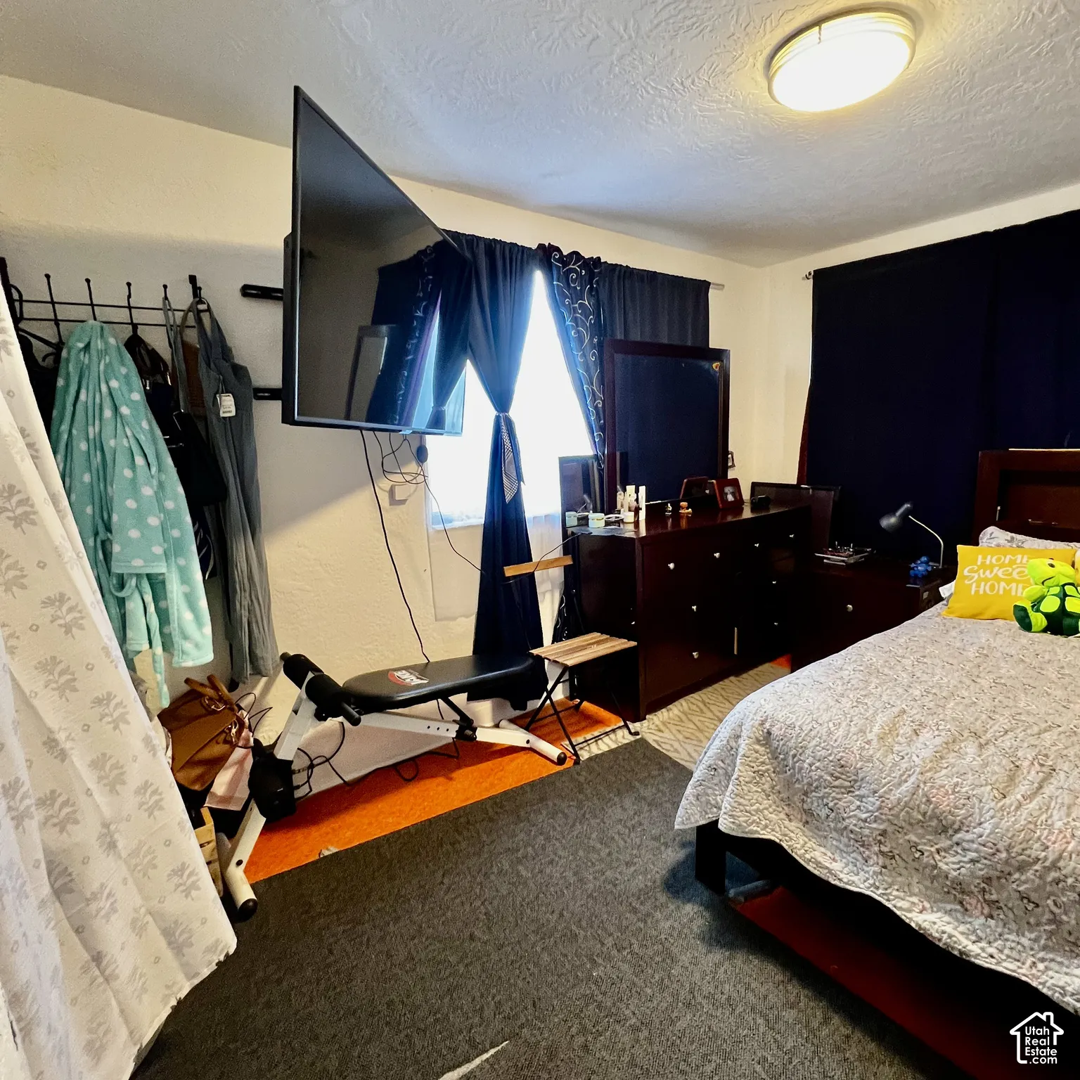 Room with textured ceiling, flush-mount lighting, and wall-mounted television bracket