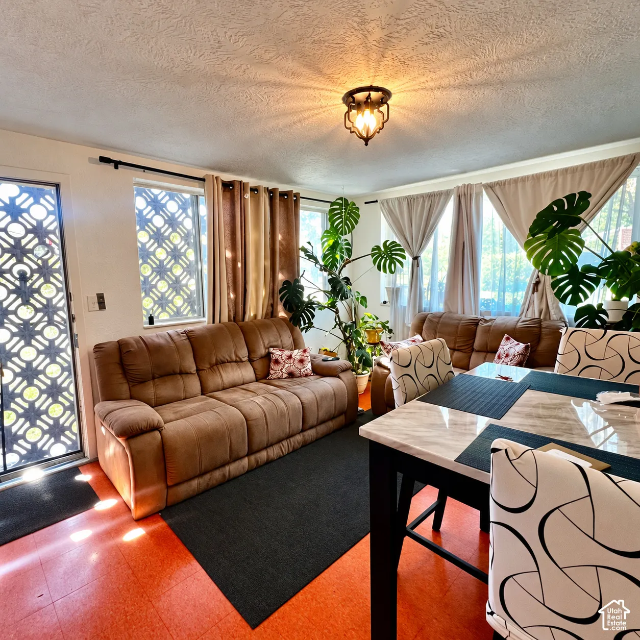 Recessed lighting, patterned security door, windows with decorative grilles, overhead decorative light fixture, and textured ceiling