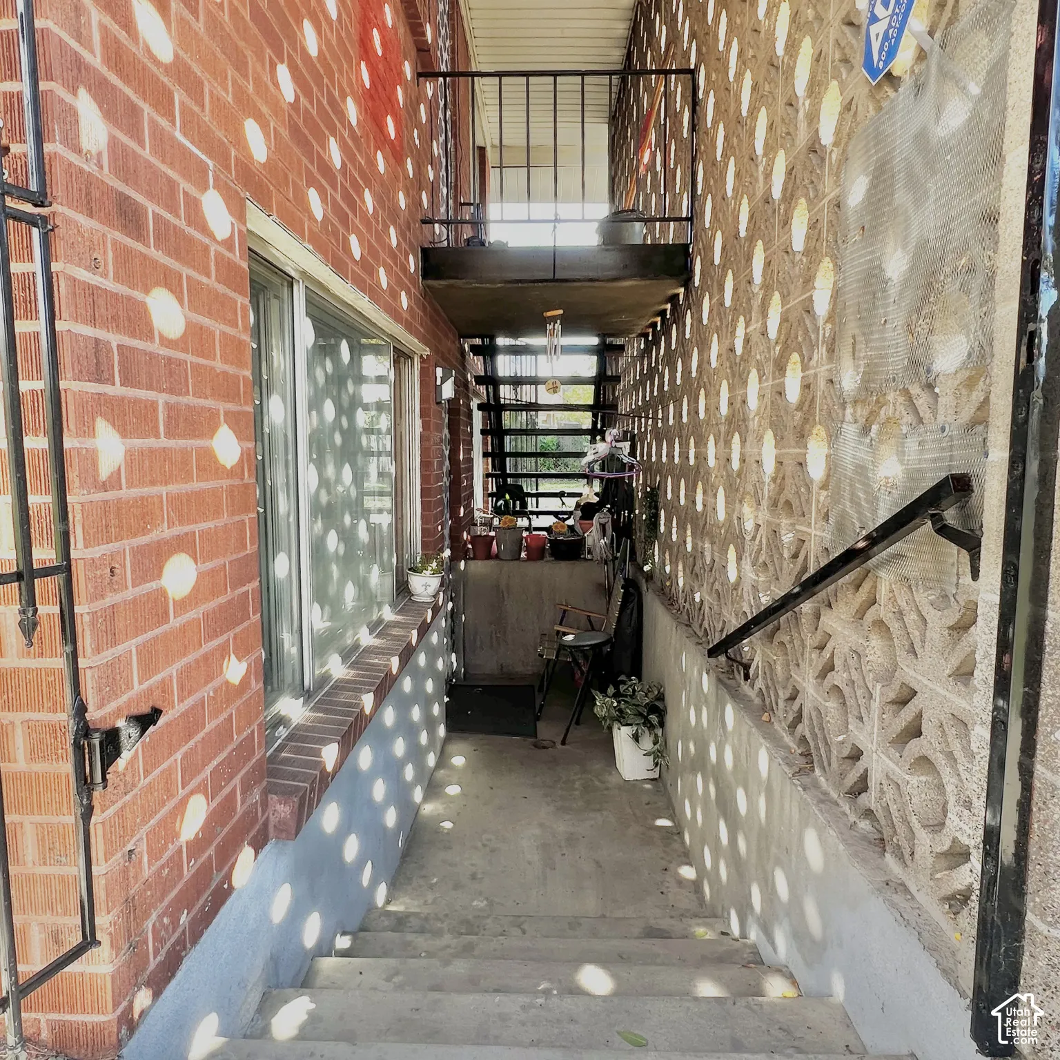 Exterior stairwell featuring red brick masonry, decorative concrete screen walling, and metal railing