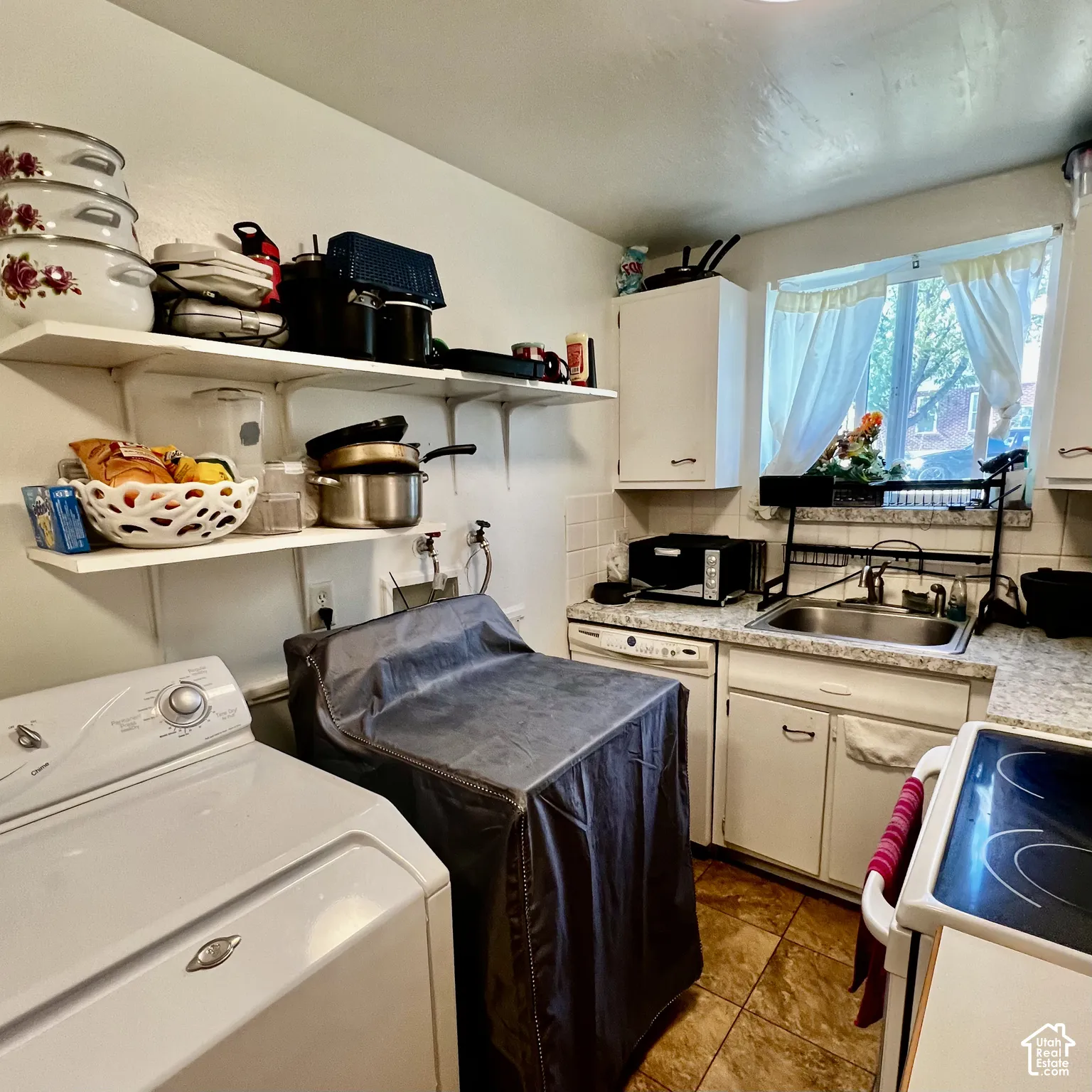Kitchen with a double basin sink, white cabinetry, and tiled flooring