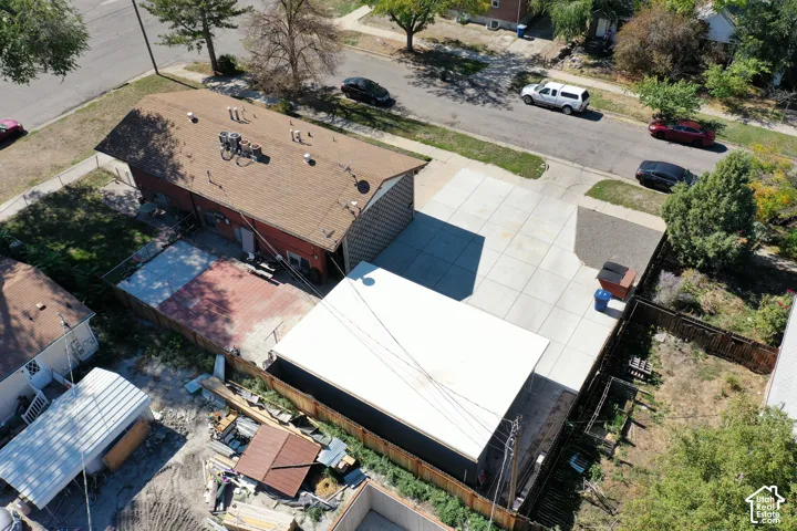 Expansive concrete driveway, fenced property, and detached outbuilding with a flat roof